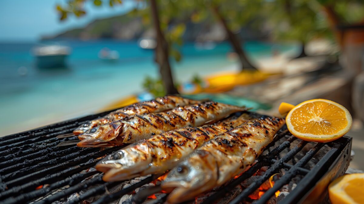 Tutu's Pantry Goodies made in Hawaii with Aloha 5 Grilled fish prepared on a barbecue sit on the grill with slices of orange, smoke rising. The fish is cooked to perfection, showcasing beautiful grill marks. In the background, there is a scene of a tropical landscape with turquoise ocean water and distant land. The scene evokes a sense of tropical cooking and can be used in various editorial and commercial contexts related to food, cooking, travel, or summer vacations.